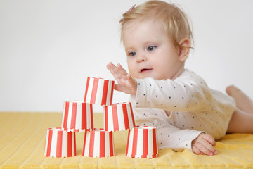 Cute baby girl playing with paper cups